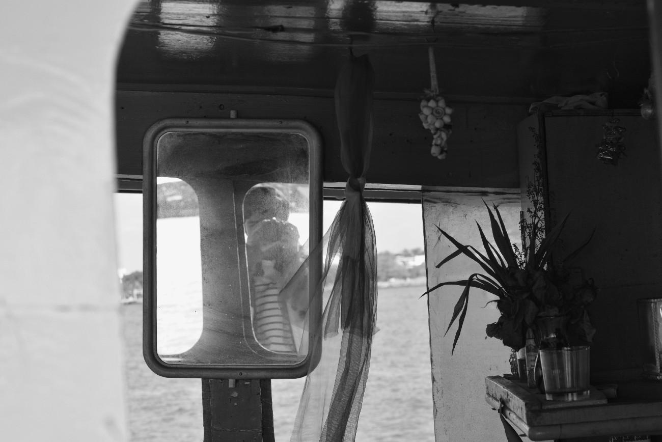 self-portrait captured through a mirror on a boat