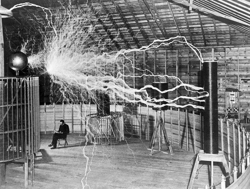 famous photography of Nikola Tesla sitting near his Tesla coil