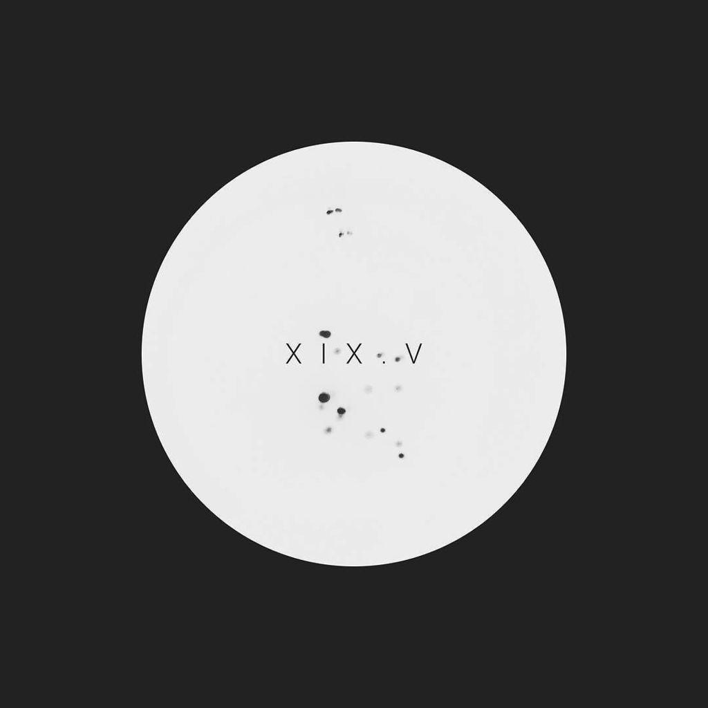 a white circle with a few black specks and 'XIX.V' in its center