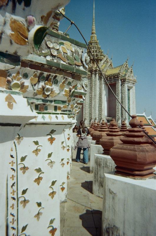 a woman walking along the jagged terrace path of Wat Arun