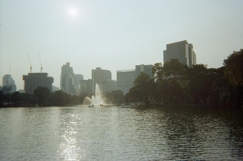 a water fountain on a lake in a city park