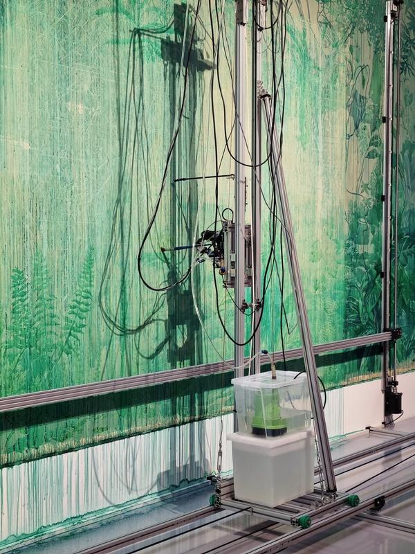 a machine paints plants on a large canvas