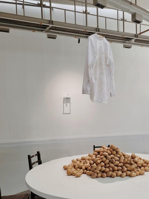 a dirty white shirt hangs above a pile of potatoes on a white round table