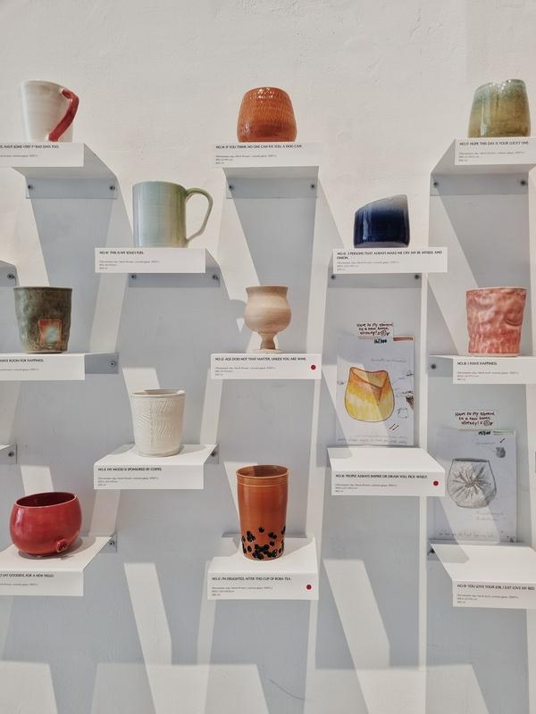 a collection of colourful ceramic mugs on display