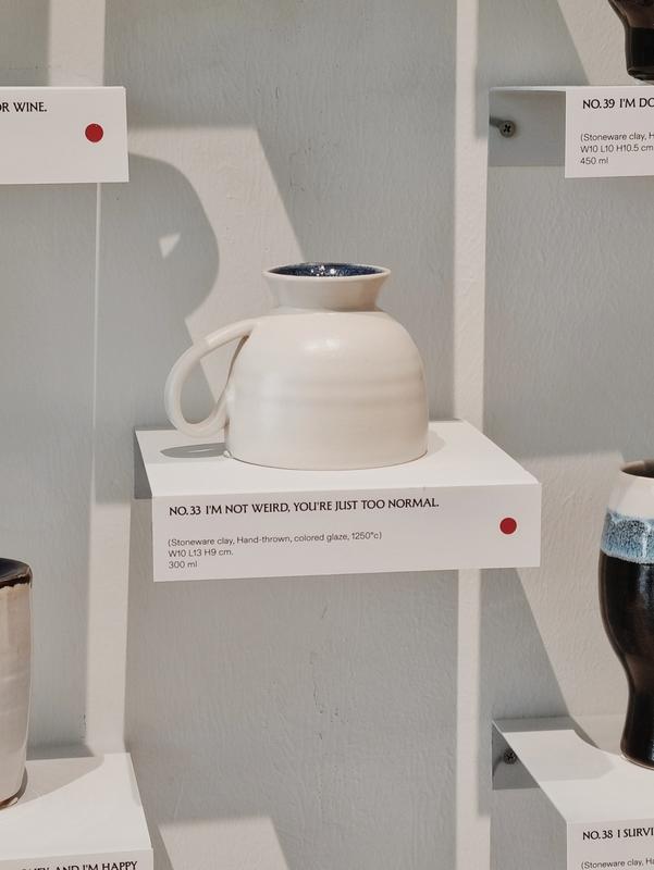 an upside-down white ceramic mug titled '№ 33 I'm not weird, you're just too normal'